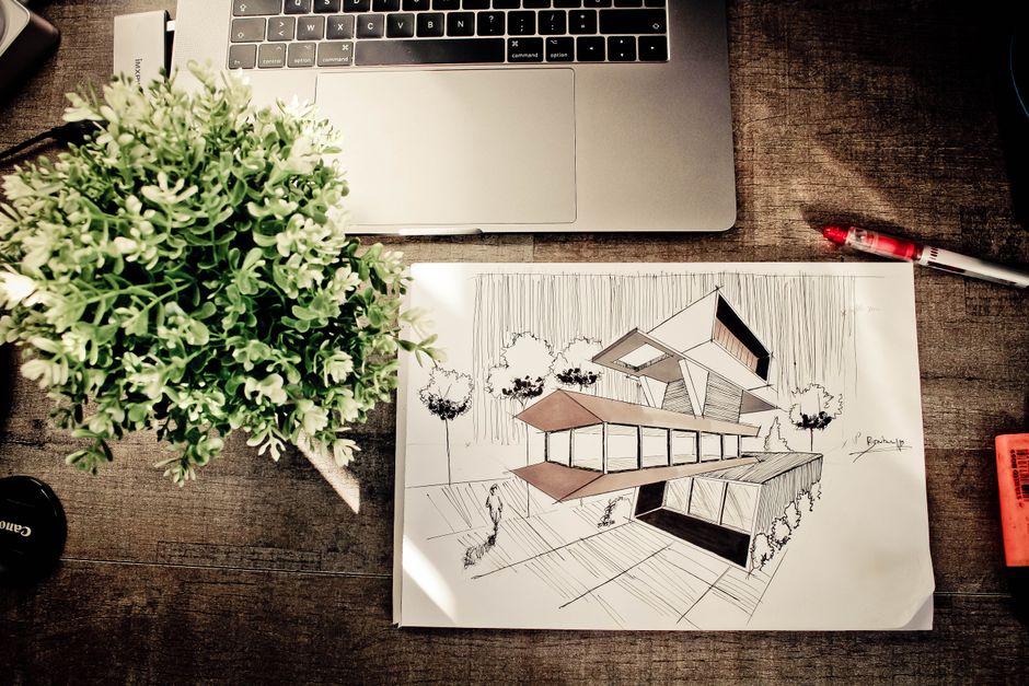 architectural site planning sketches on a wooden table with greenery